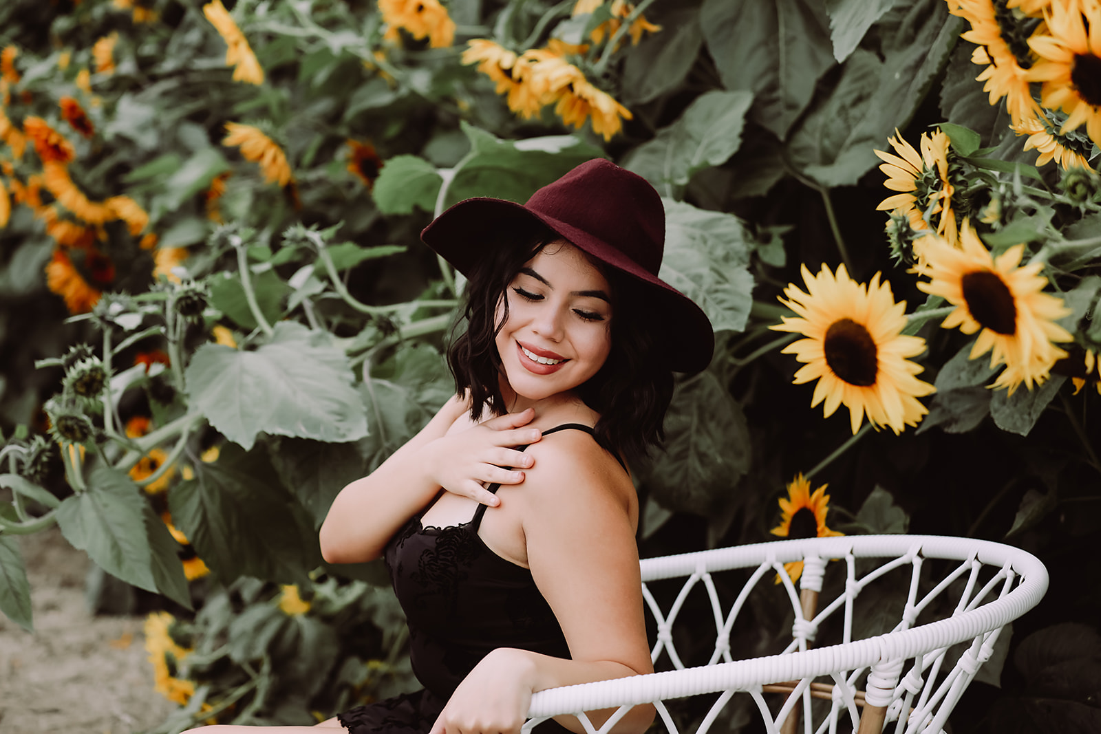 Client in a wide-brim hat seated among sunflowers