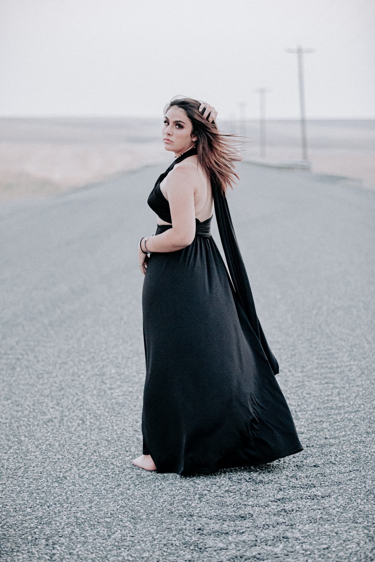 Senior in a flowing black gown on an open country road