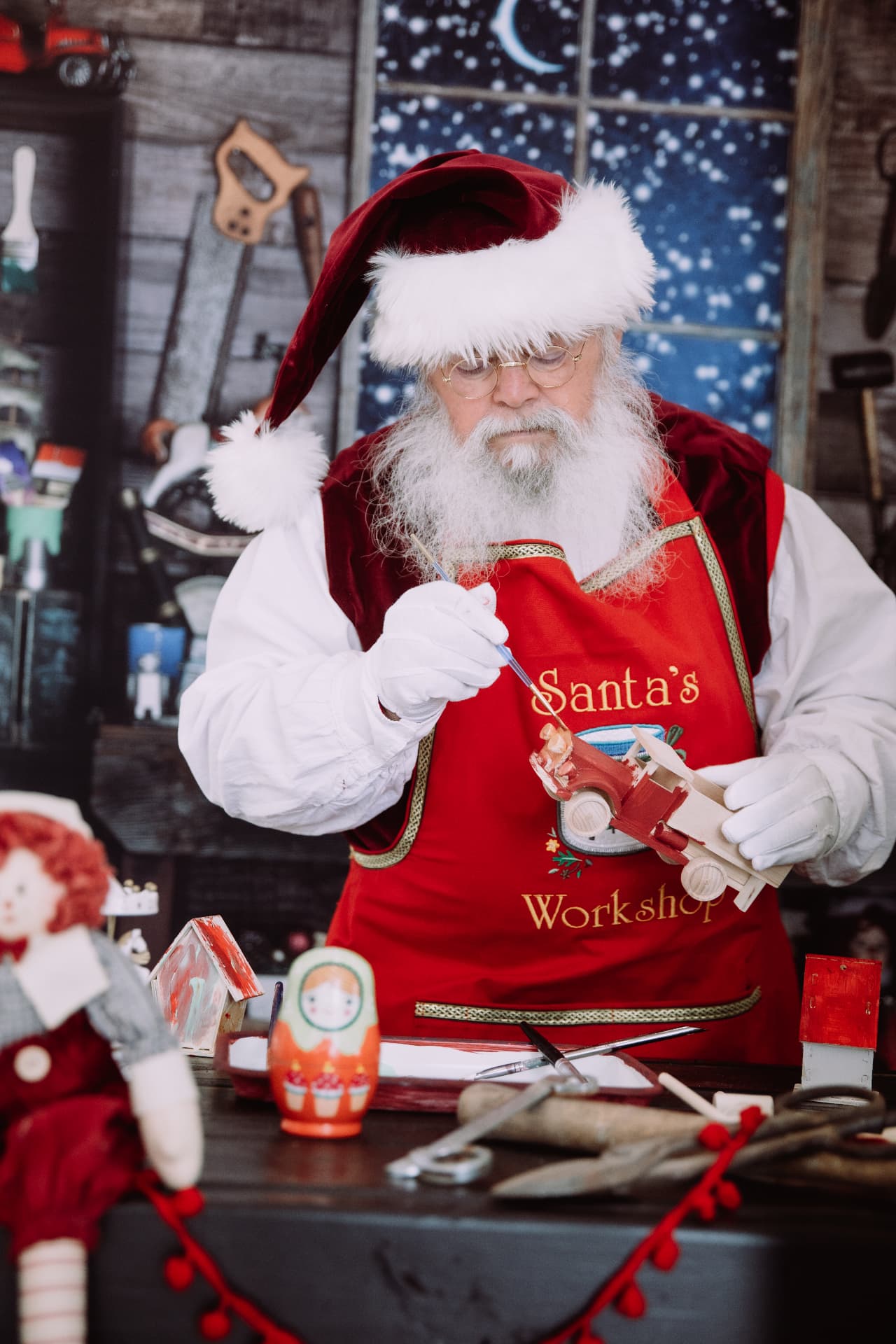 Santa hand-painting a wooden toy truck in his workshop