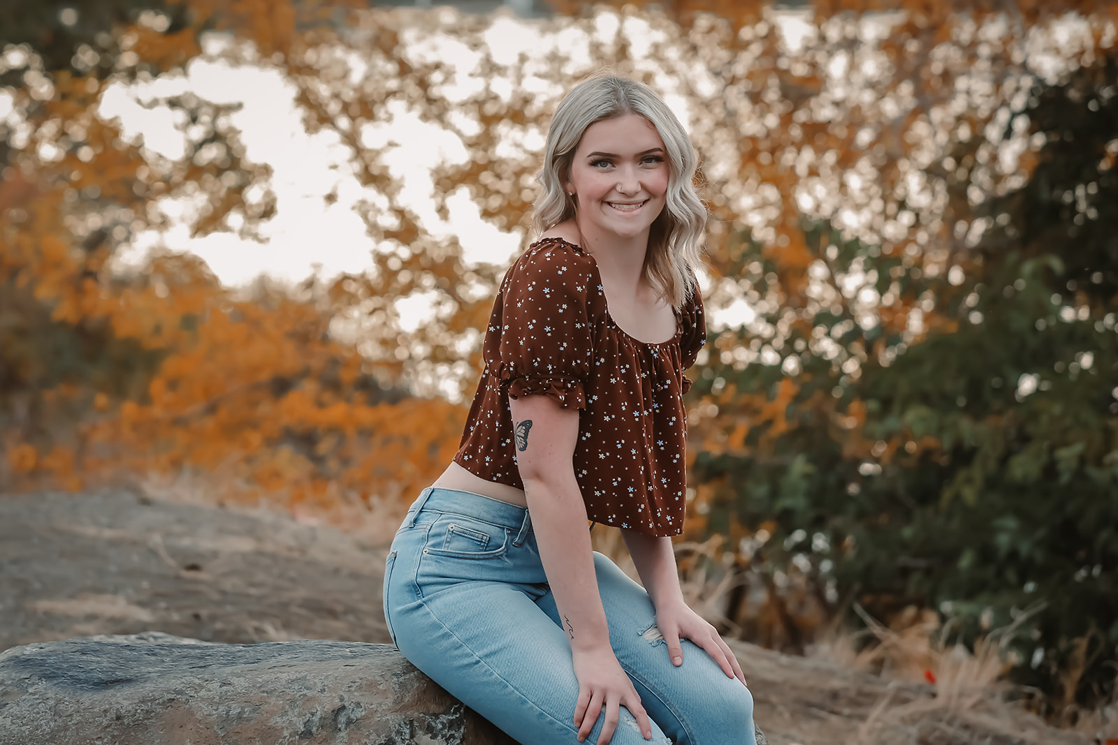 Senior seated on a rock surrounded by warm fall foliage