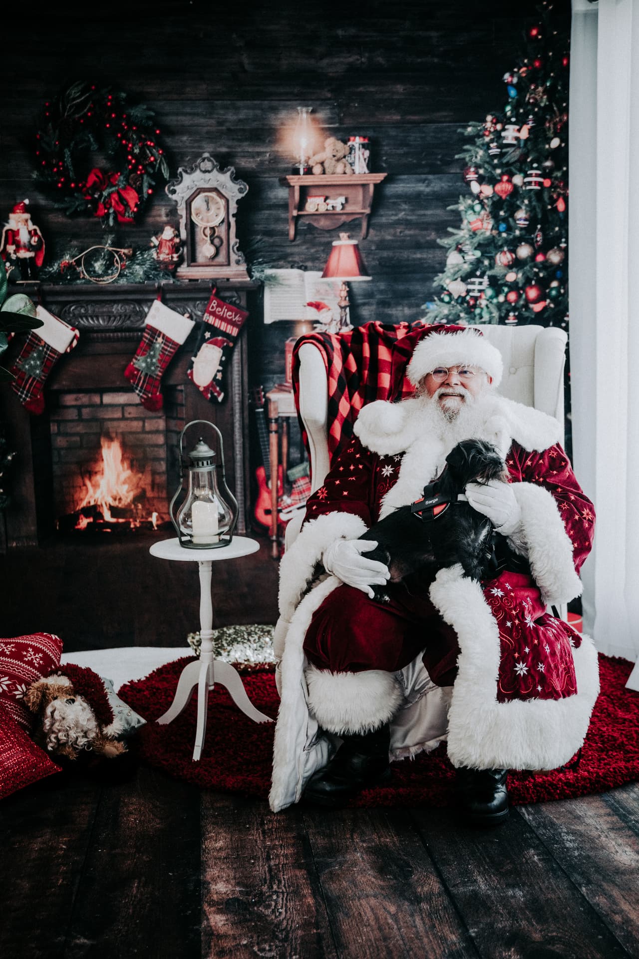Santa holding a family dog in the fireside Christmas set