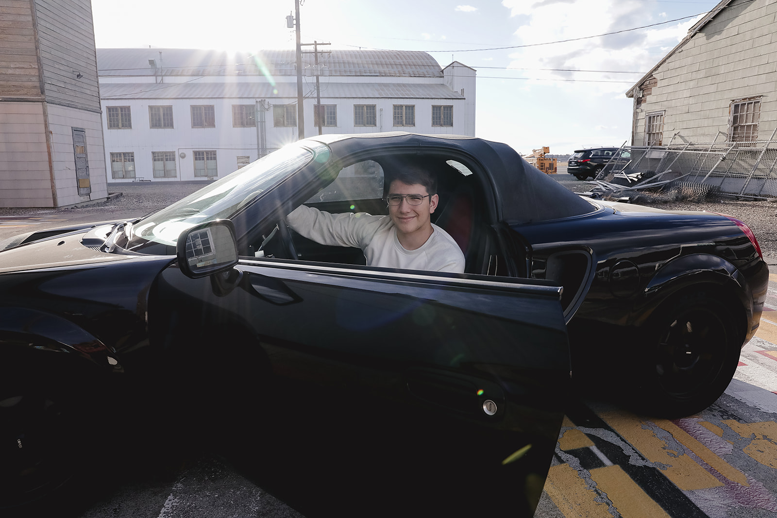 Senior seated in a black convertible with the door open