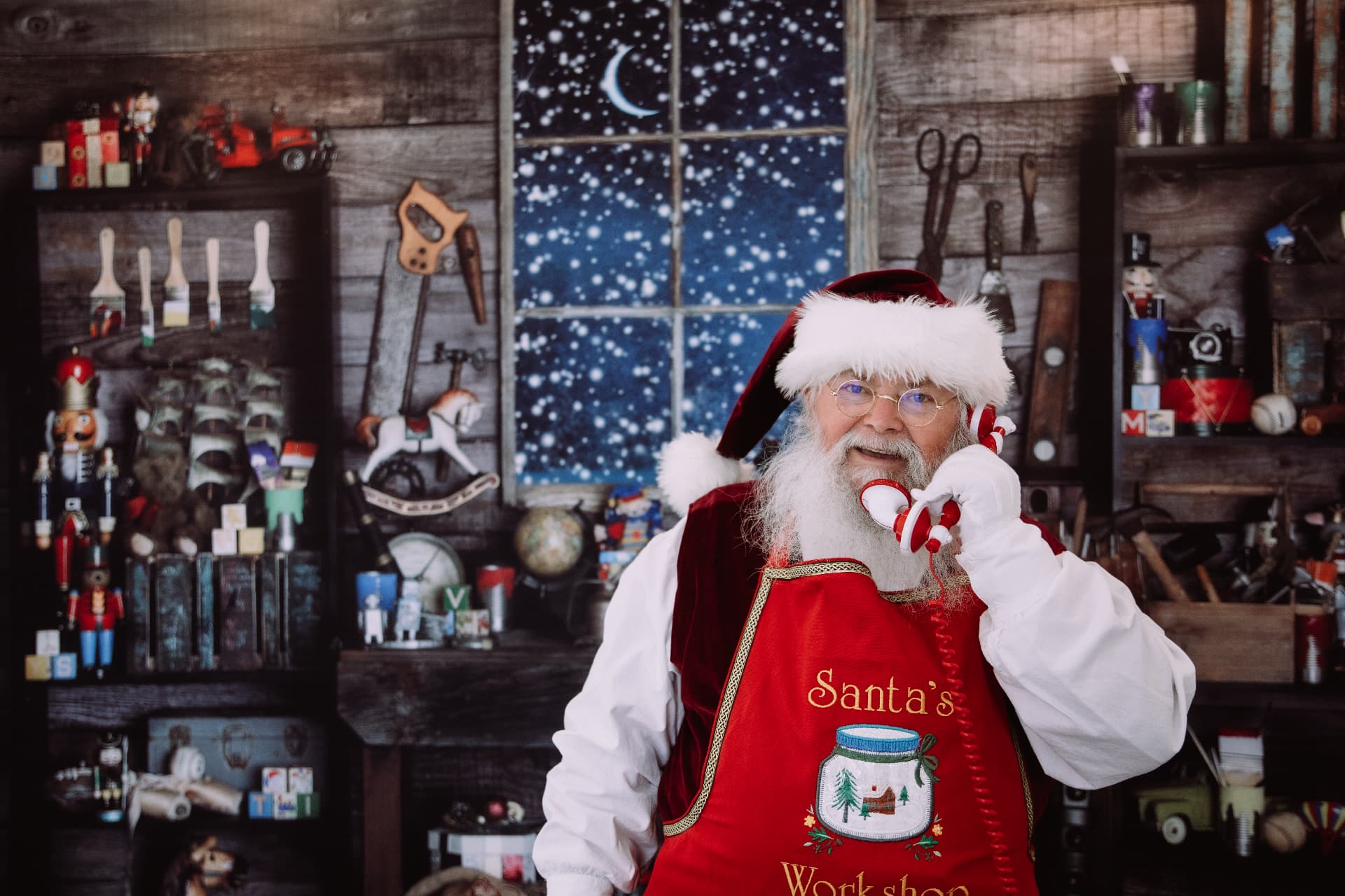 Santa taking a call in his snowy workshop