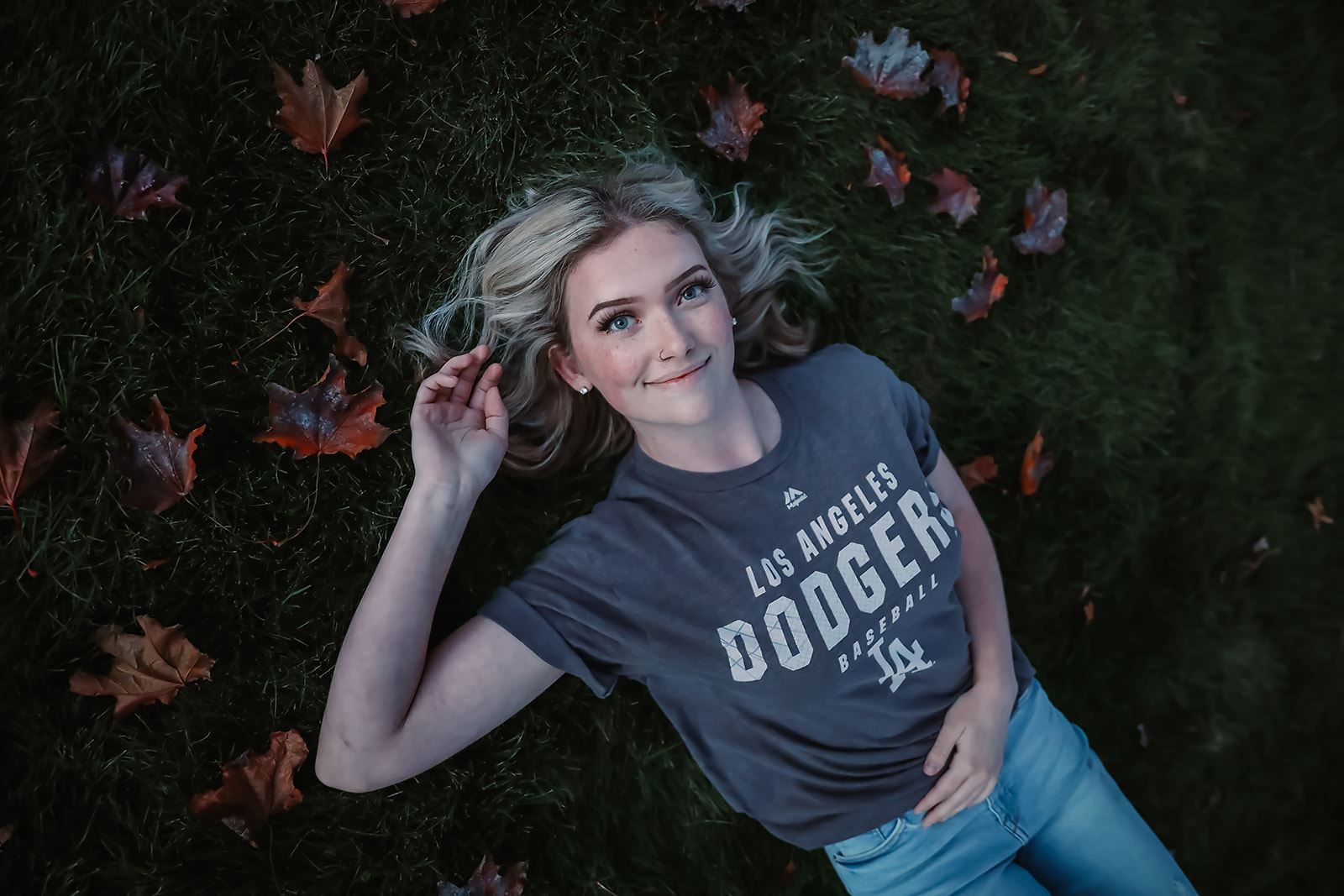 Senior lying in the grass among fallen autumn leaves
