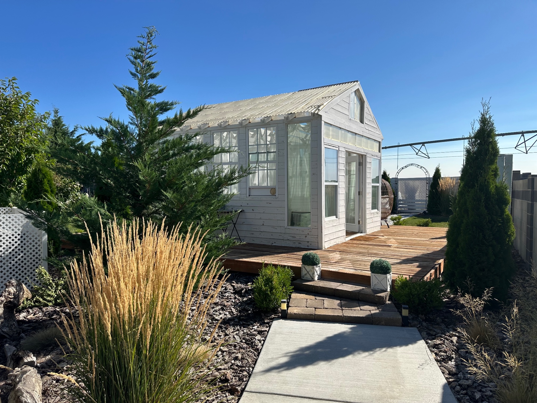 The Glasshouse exterior in daylight with wooden deck and landscaped path