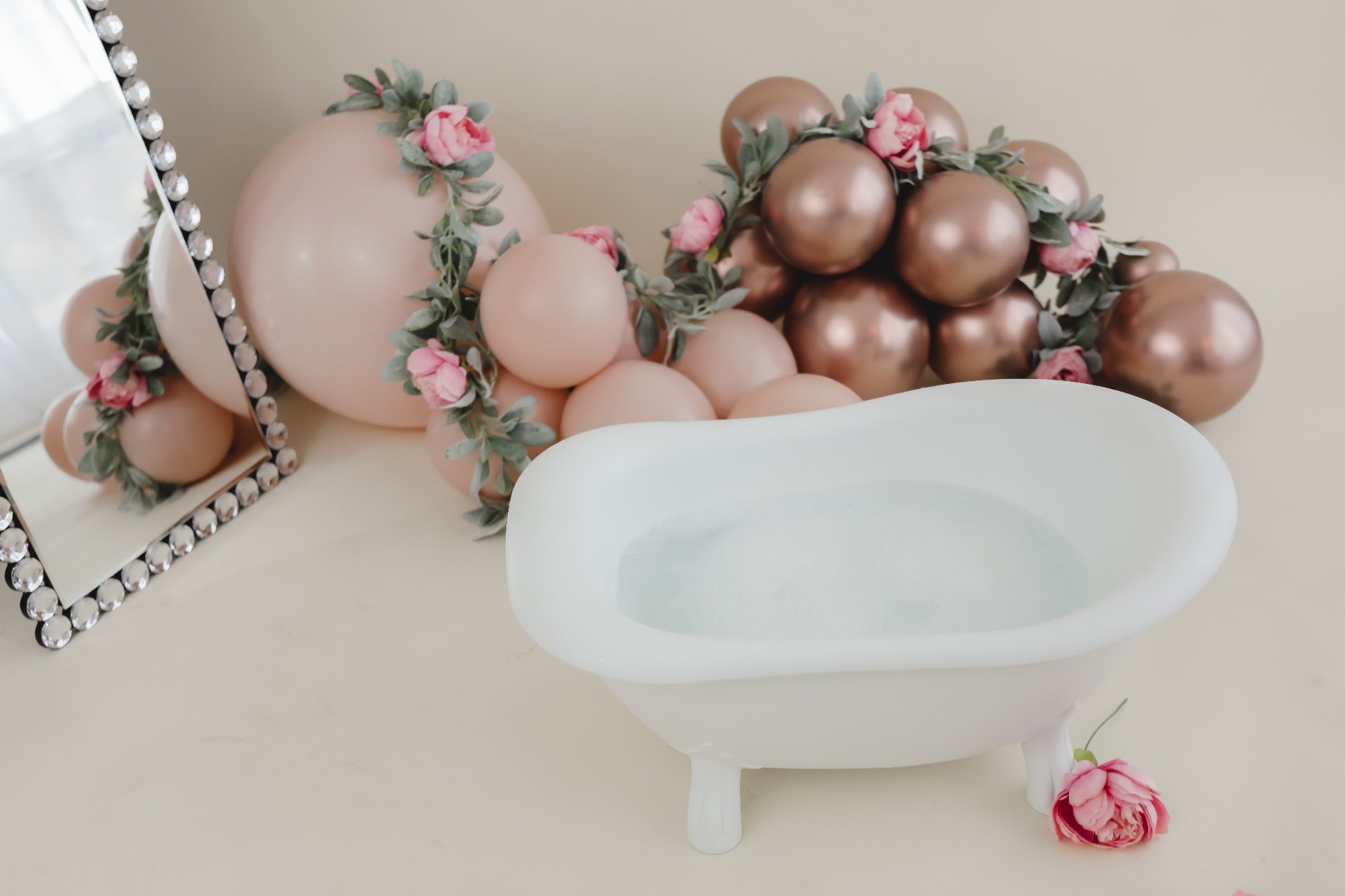 Blush and rose-gold balloon splash set with a white clawfoot tub for a cake smash session