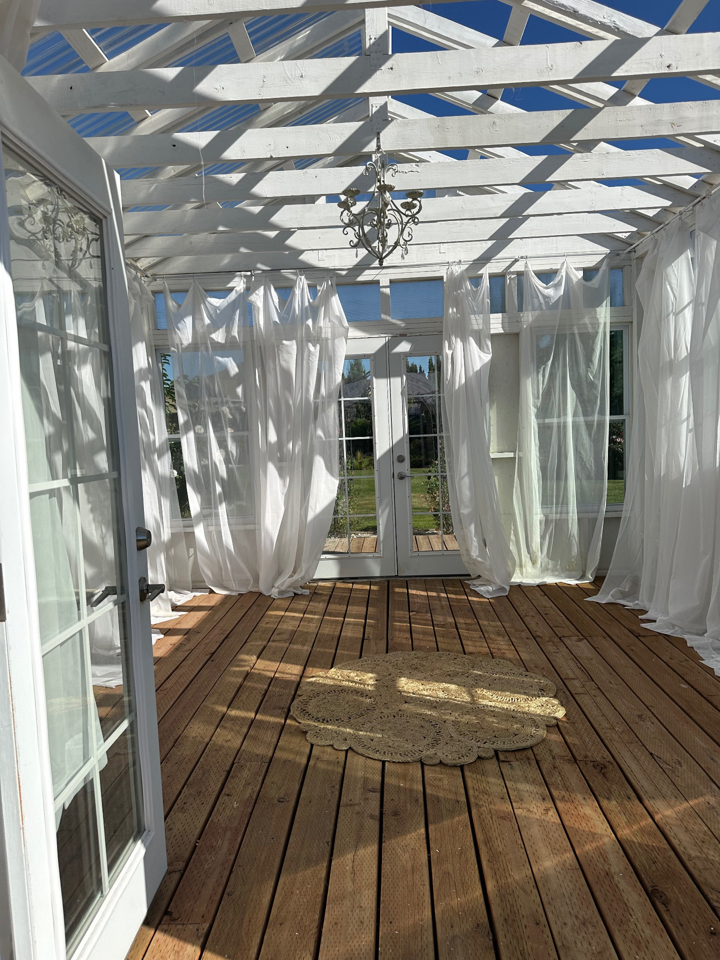 Inside The Glasshouse with sheer white drapes and vintage chandelier