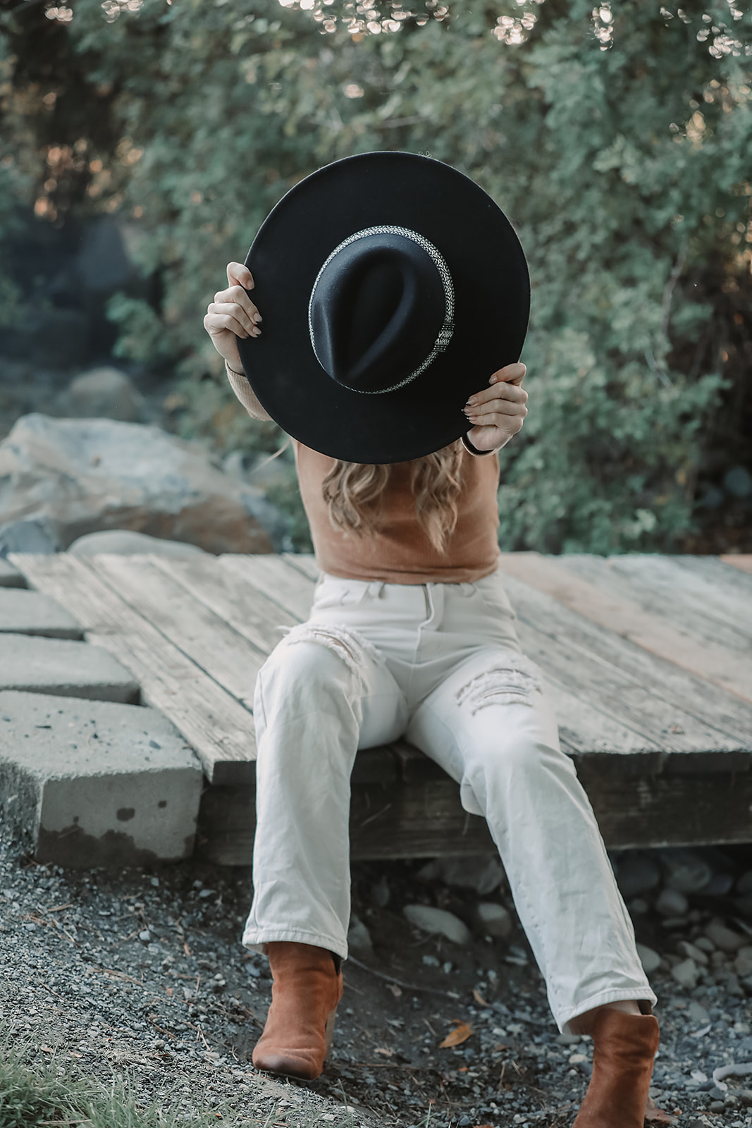 Senior playfully hiding behind her black wide-brim hat