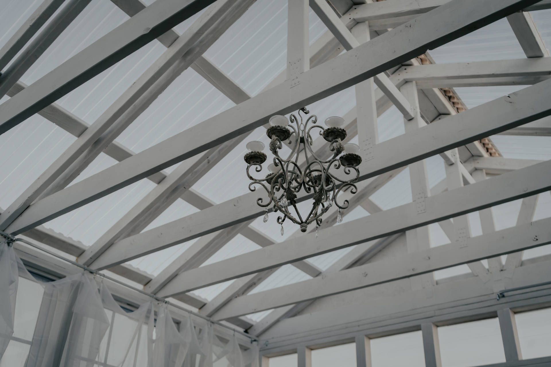Vintage chandelier suspended from white ceiling beams