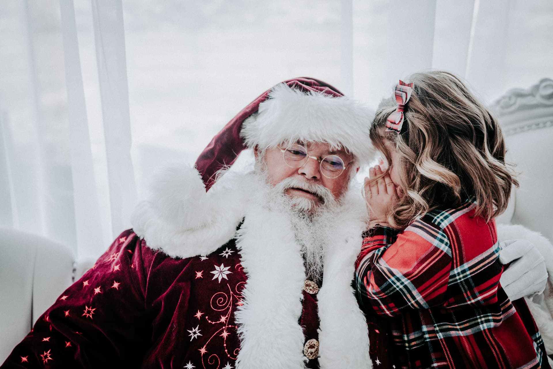 Little girl whispering her Christmas wish into Santa's ear