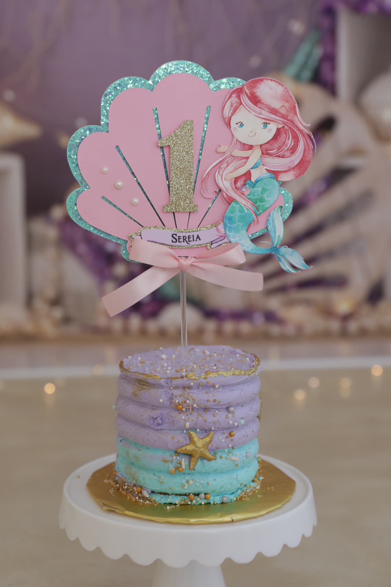 Pastel mermaid smash cake with a gold glitter number one topper