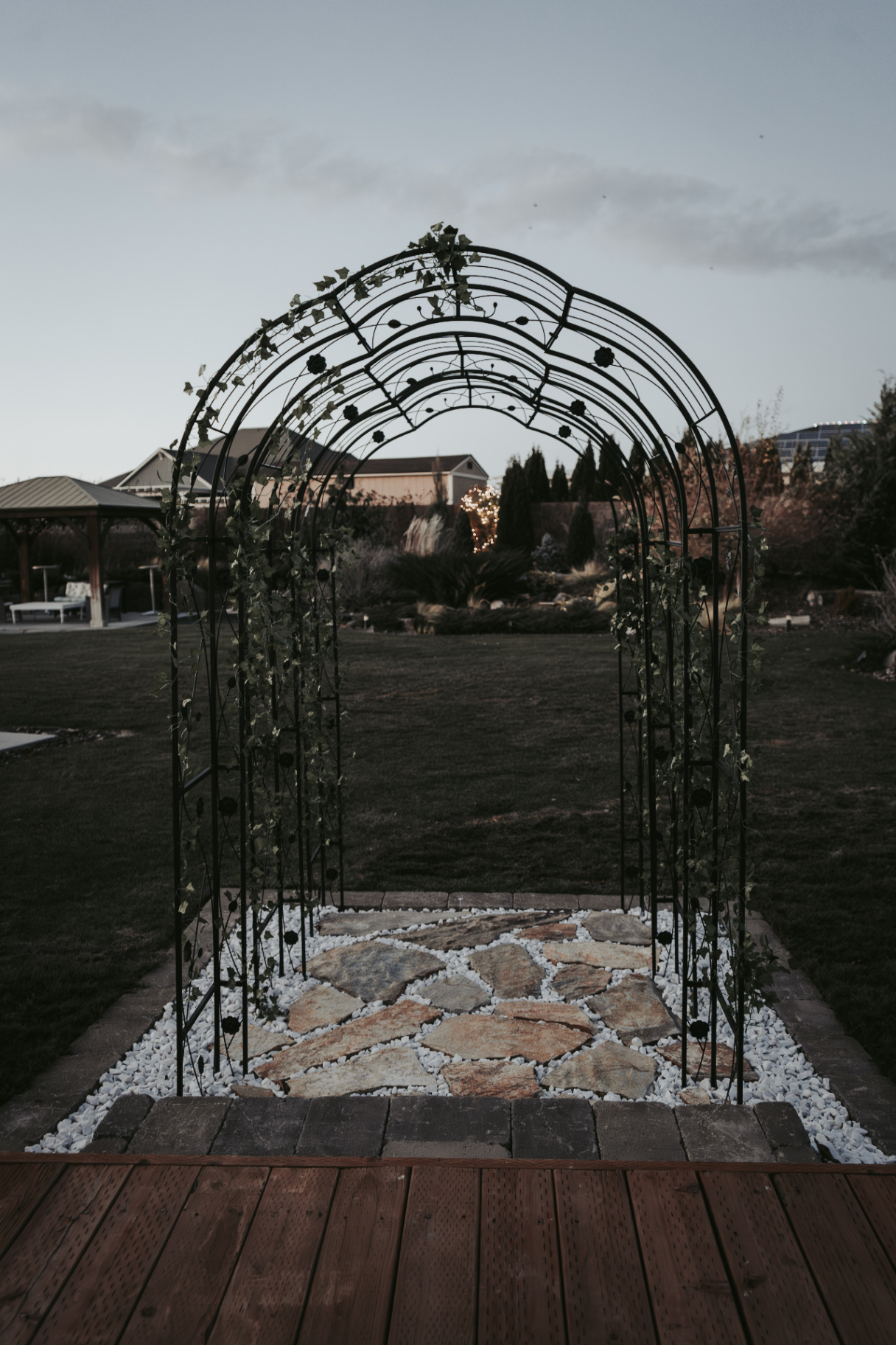 Ivy-wrapped iron arbor over stone pathway