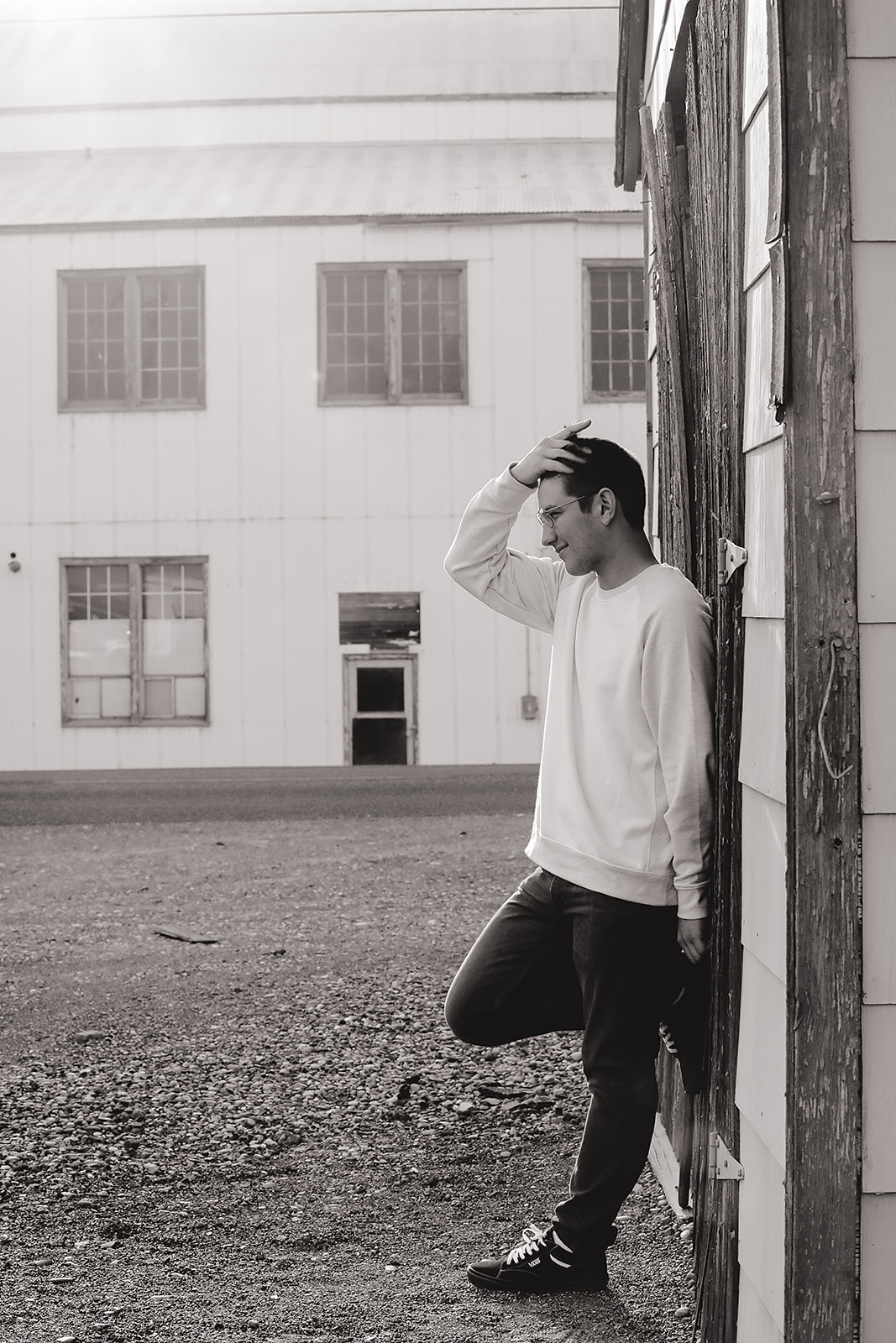 Senior leaning against a weathered door in a black and white portrait